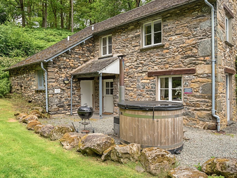 An outdoor area with a stone house and a hot tub at Hammerhole at the Graythwaite Estate Graythwaite Estate near Hawkshead