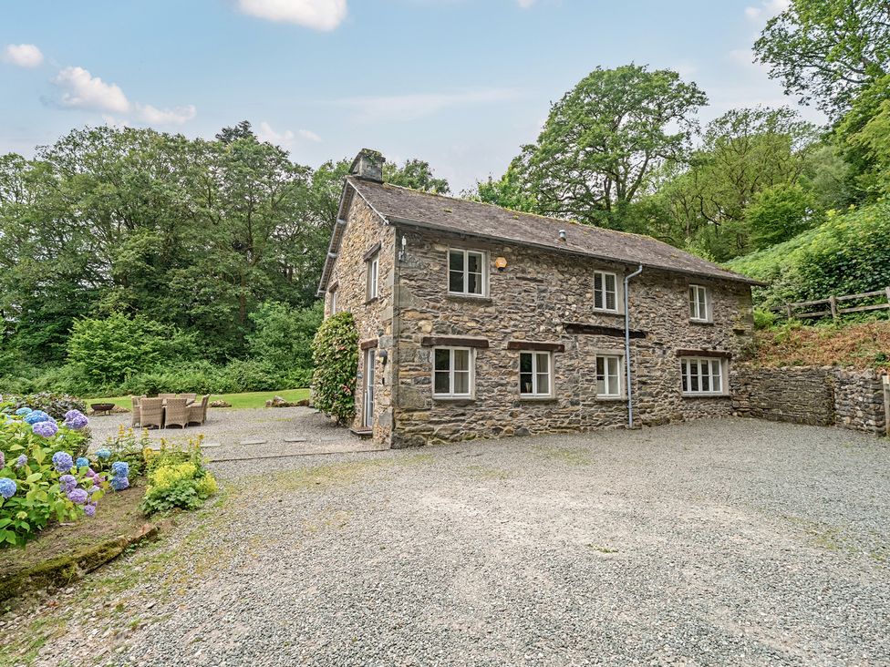 A stone house with a gravel driveway and seating area at Hammerhole at the Graythwaite Estate near Hawkshead