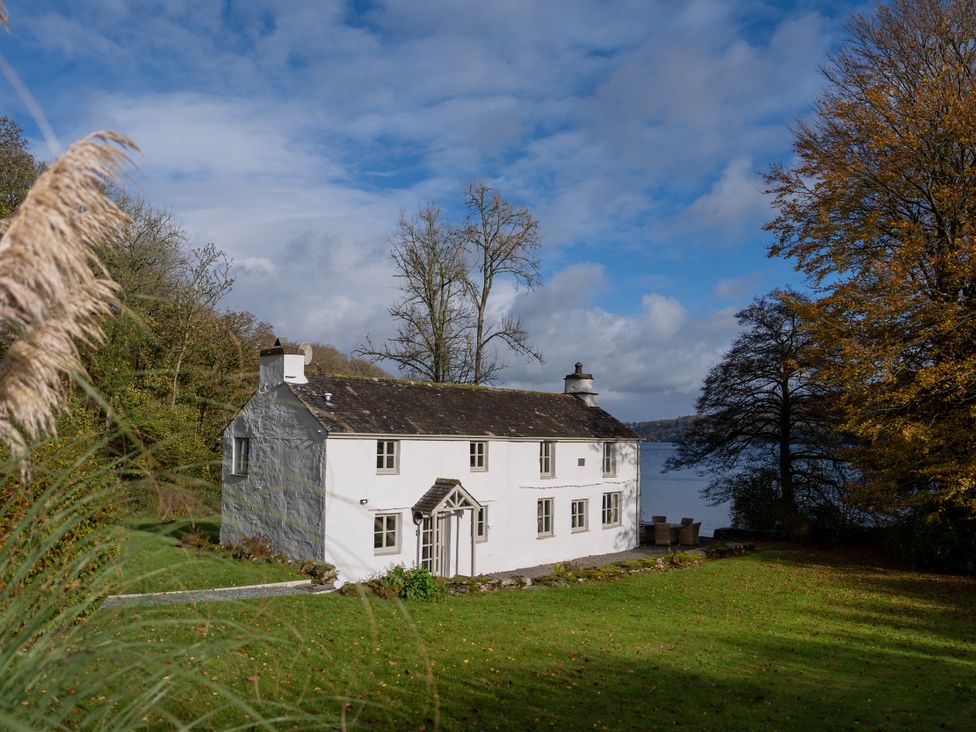 A house near a lake surrounded by trees at Hullet Hall in Graythwaite near Hawkshead