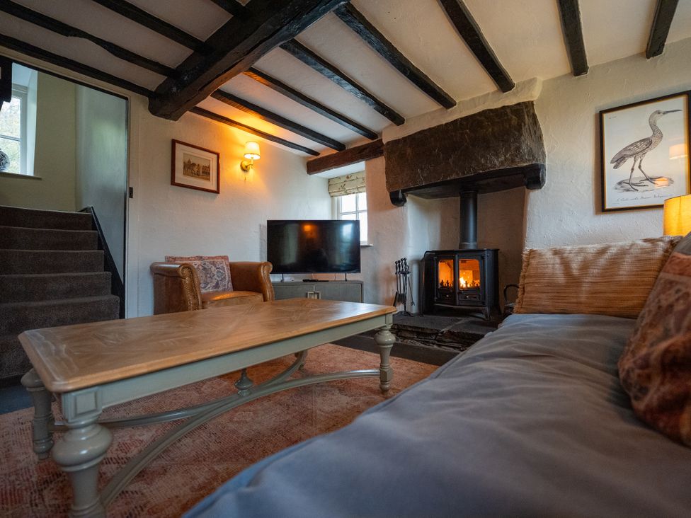 A living room with a fireplace and television at Hullet Hall in Graythwaite near Hawkshead