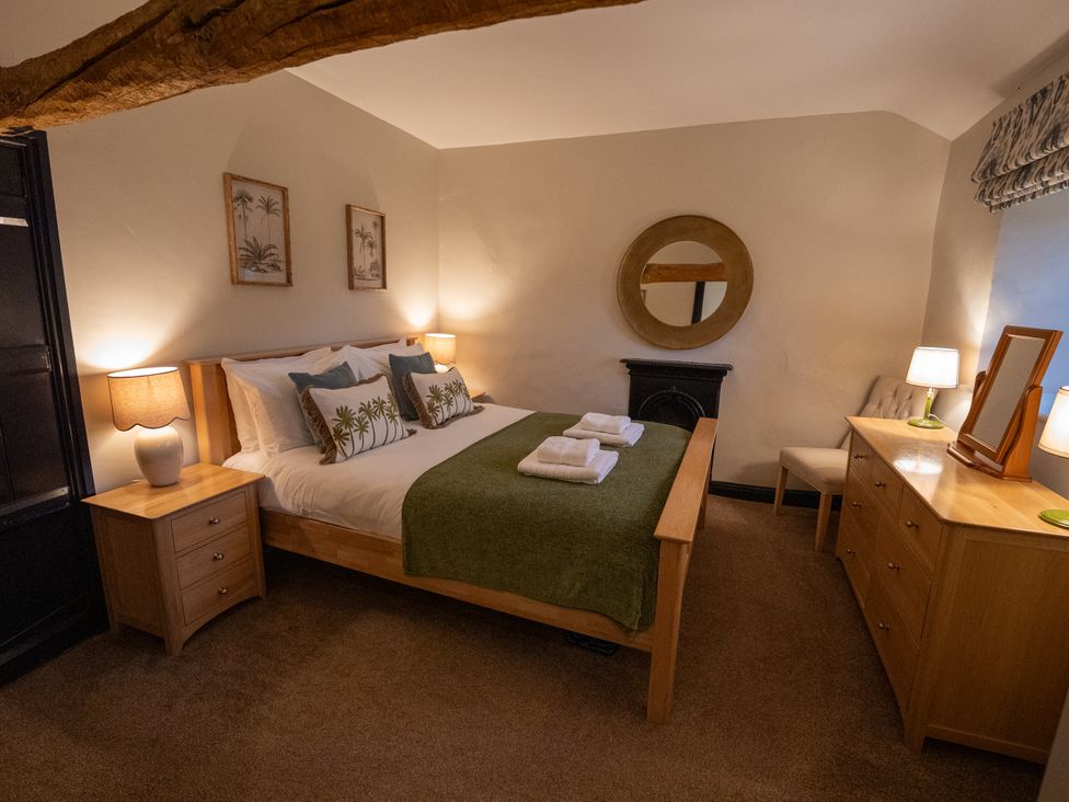 A bedroom with a bed, nightstand, and dressing table at Hullet Hall in Graythwaite near Hawkshead