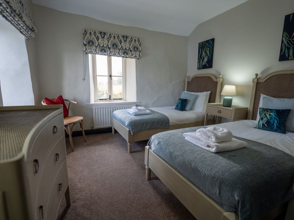 A bedroom with two beds and a dressing table at Hullet Hall in Graythwaite near Hawkshead