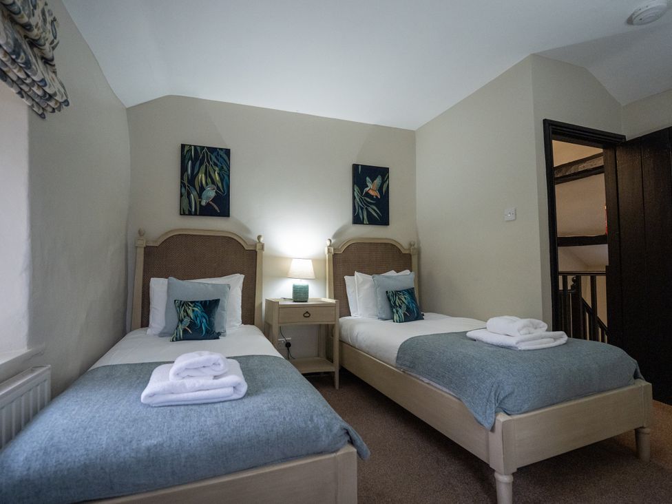 A bedroom with two beds and a bedside table at Hullet Hall in Graythwaite near Hawkshead