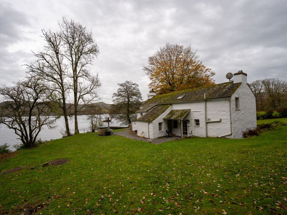 A house next to a lake with grass and trees at Hullet Hall in Graythwaite near Hawkshead