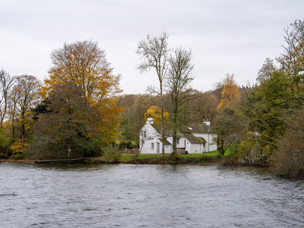 A house beside a river with trees at Hullet Hall in Graythwaite near Hawkshead
