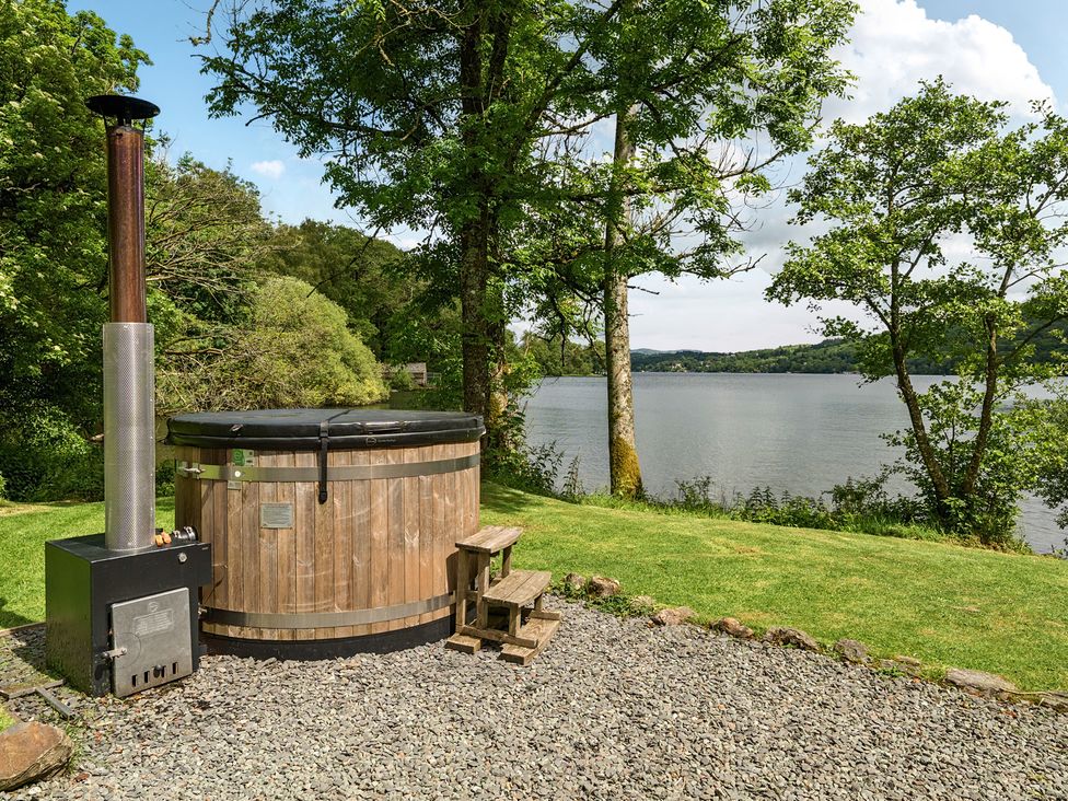A hot tub with a wooden structure beside a lake at Hullet Hall at the Graythwaite Estate near Hawkshead