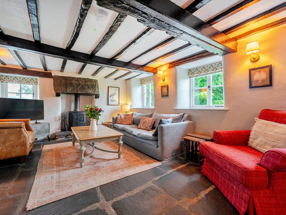 A living room with a sofa, armchair, coffee table and fireplace at Hullet Hall at the Graythwaite Estate near Hawkshead