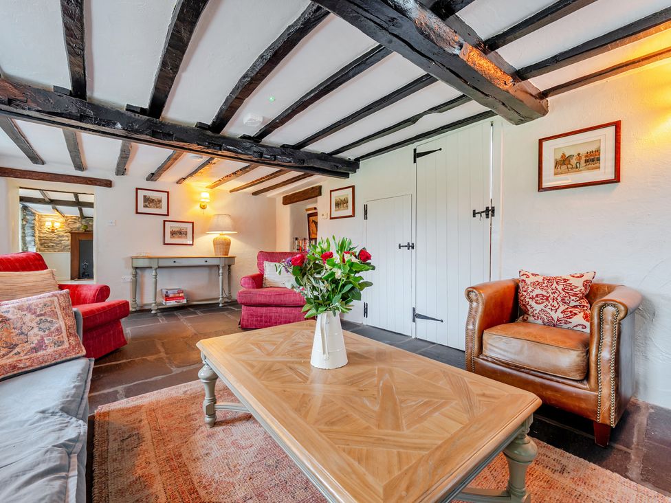 A living room with a sofa, armchair, and coffee table at Hullet Hall at the Graythwaite Estate near Hawkshead
