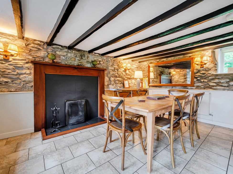 A dining room with a fireplace and wooden table at Hullet Hall at the Graythwaite Estate near Hawkshead