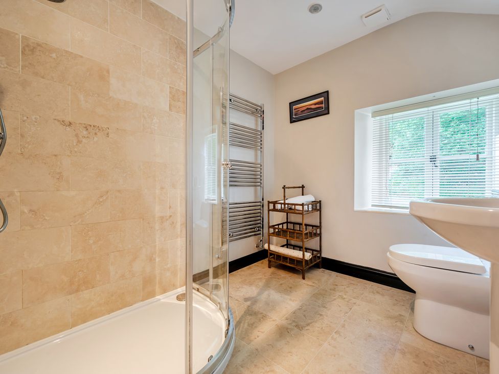 A bathroom with a shower, toilet, and towel storage at Hullet Hall at the Graythwaite Estate near Hawkshead