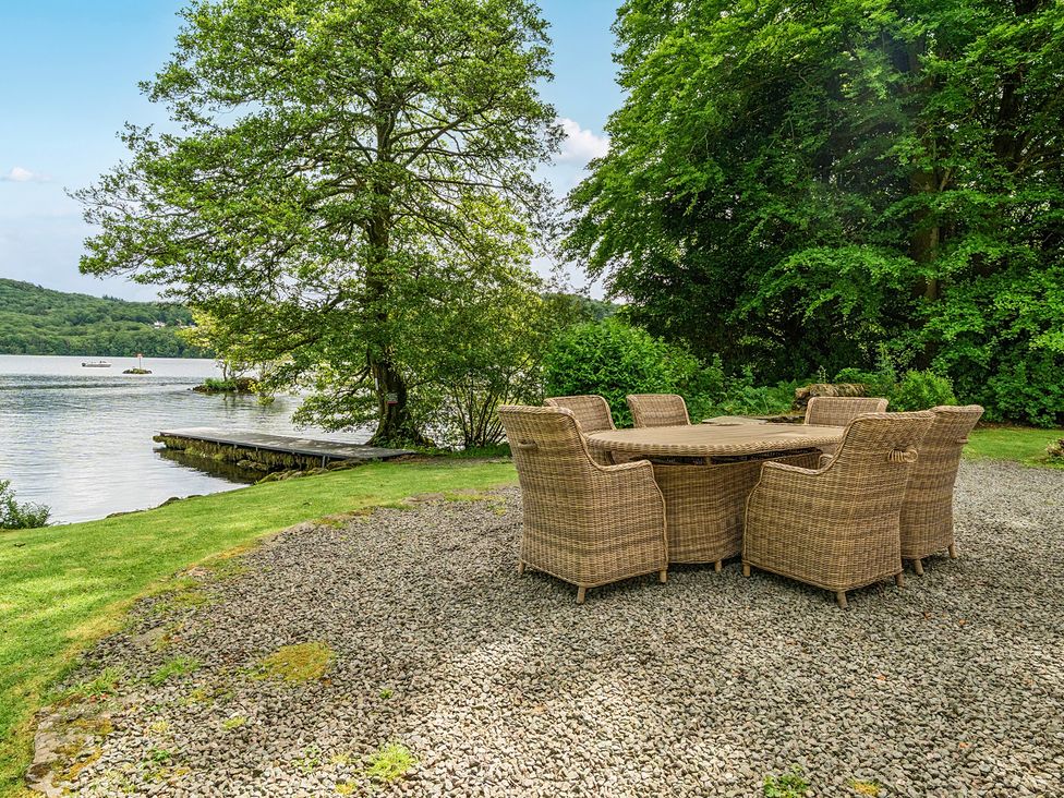 A dining table and chairs by the water at Hullet Hall at the Graythwaite Estate near Hawkshead