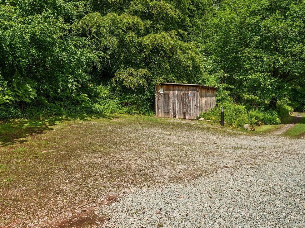A shed in an outdoor area with gravel and trees at Hullet Hall at the Graythwaite Estate near Hawkshead