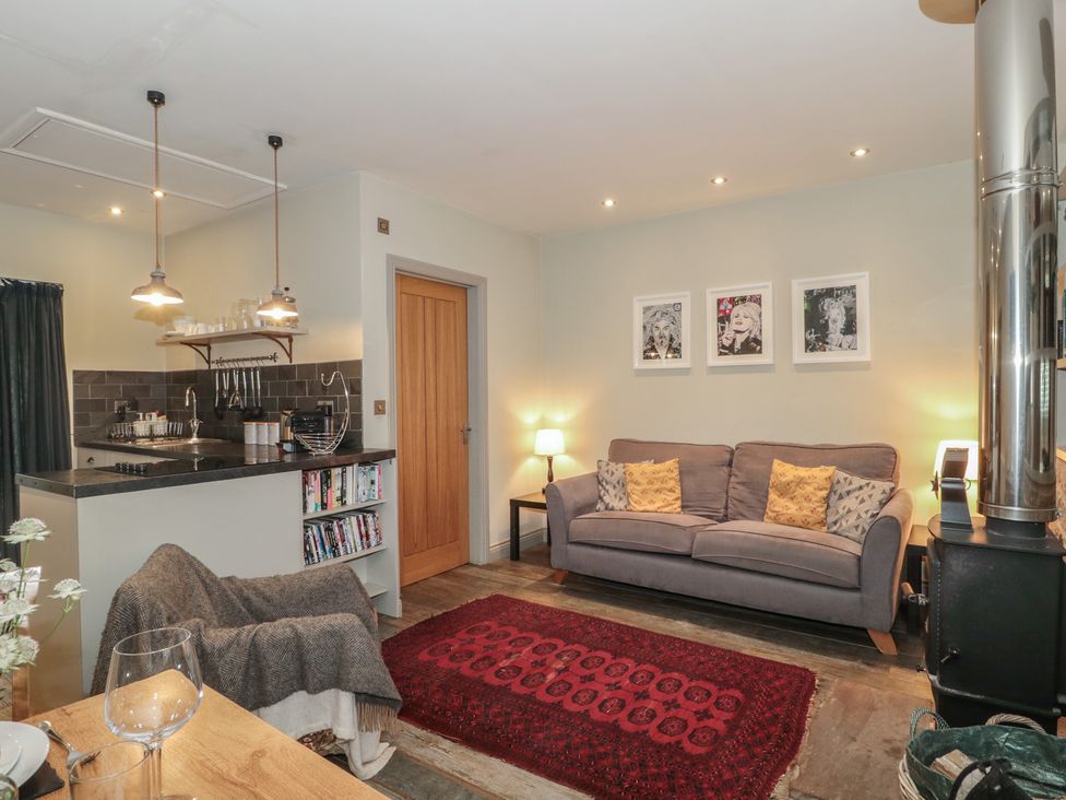 A living room with a sofa and kitchen area at The Stable in Deepdean near Ross-on-Wye