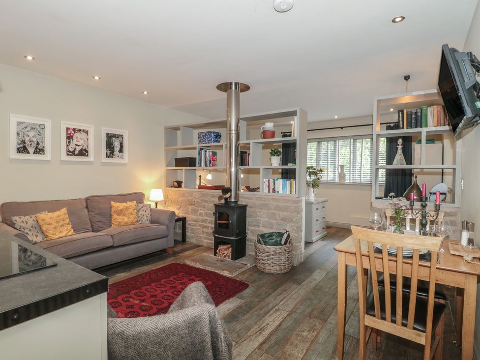 A living room with a sofa, wooden stove, and dining area at The Stable in Deepdean near Ross-on-Wye