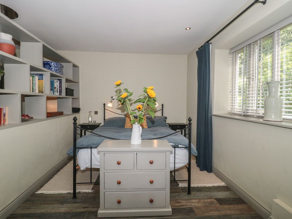 A bedroom with a bed and shelf with books at The Stable Deepdean near Ross-on-Wye