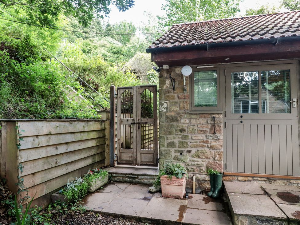 An outdoor area with a wooden gate and stone wall at The Stable in Deepdean near Ross-on-Wye