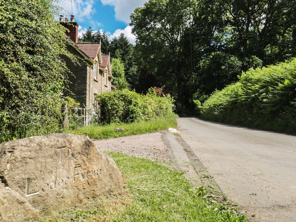 A stone sign and house by a road at The Lodge Farm in Deepdean near Ross-on-Wye