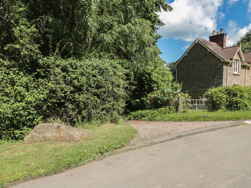 An outdoor view showing The Lodge Farm sign and surrounding greenery near the house in Deepdean near Ross-on-Wye