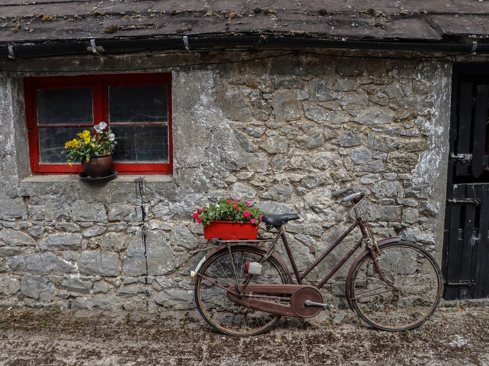 A bicycle next to a stone wall with a window and flower pots at Ryan's Loft Ardfinnan near Clonmel, County Tipperary