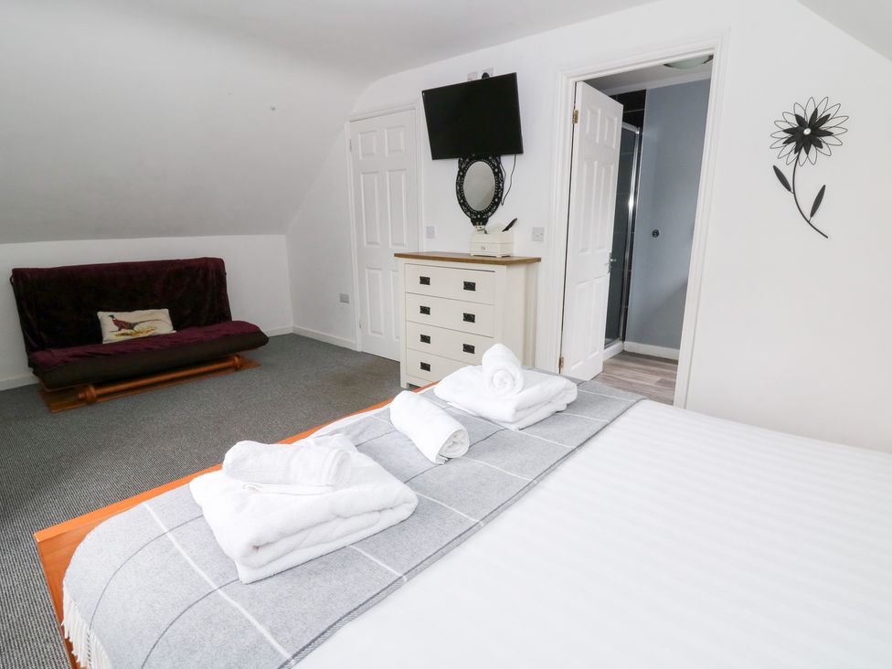 A bedroom with a bed and television at Cariad Cottage in Cross Inn