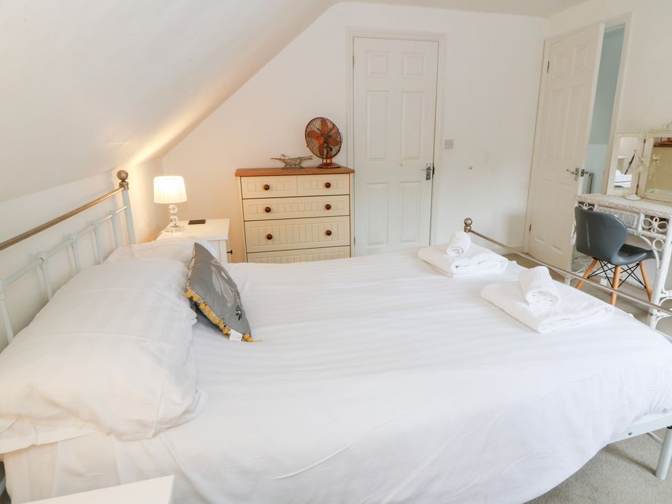 A bedroom with a bed, dresser, lamp and mirror at Cariad Cottage Cross Inn