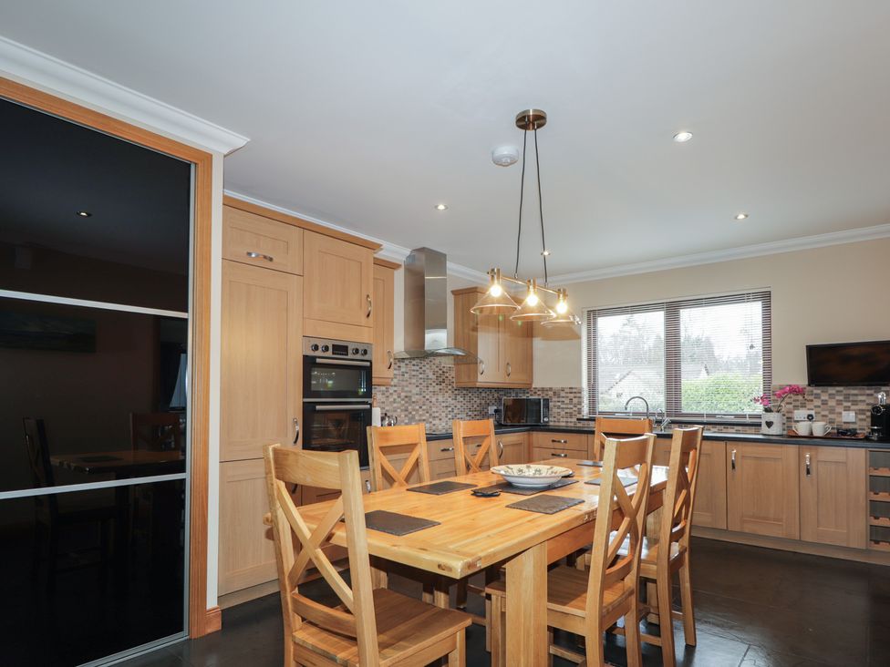 A kitchen with wooden table and chairs at Little Chestnut in Muir of Ord