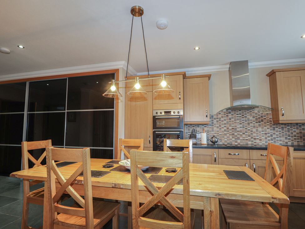 A kitchen with a wooden table and chairs at Little Chestnut in Muir of Ord