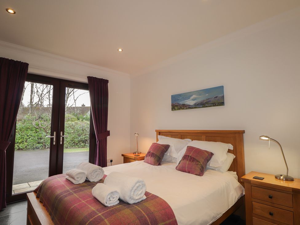 A bedroom with a double bed and sliding doors at Little Chestnut in Muir of Ord