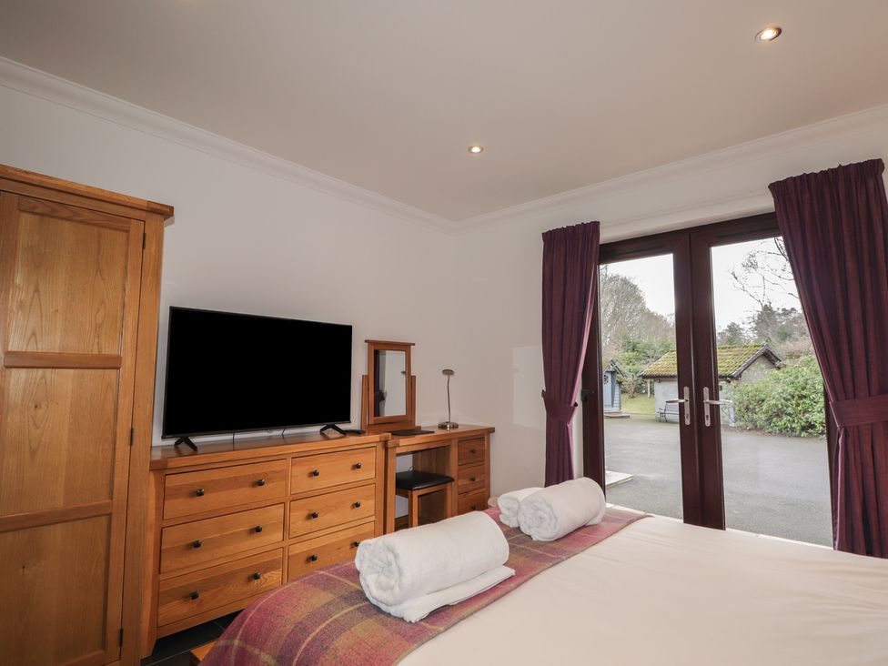 A bedroom with a bed, television, and dressing table at Little Chestnut in Muir of Ord