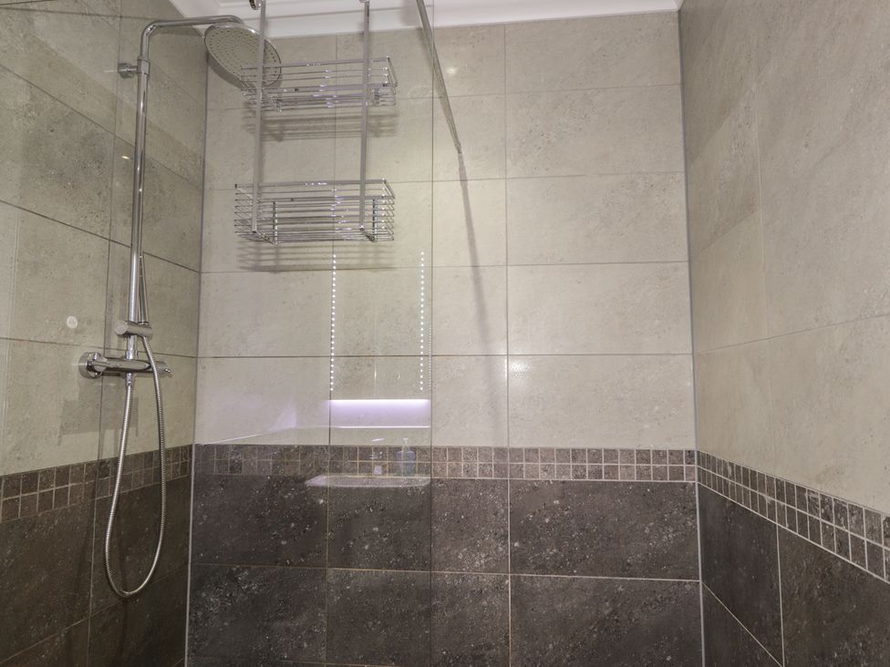 A shower with tiles and a glass panel at Little Chestnut in Muir of Ord