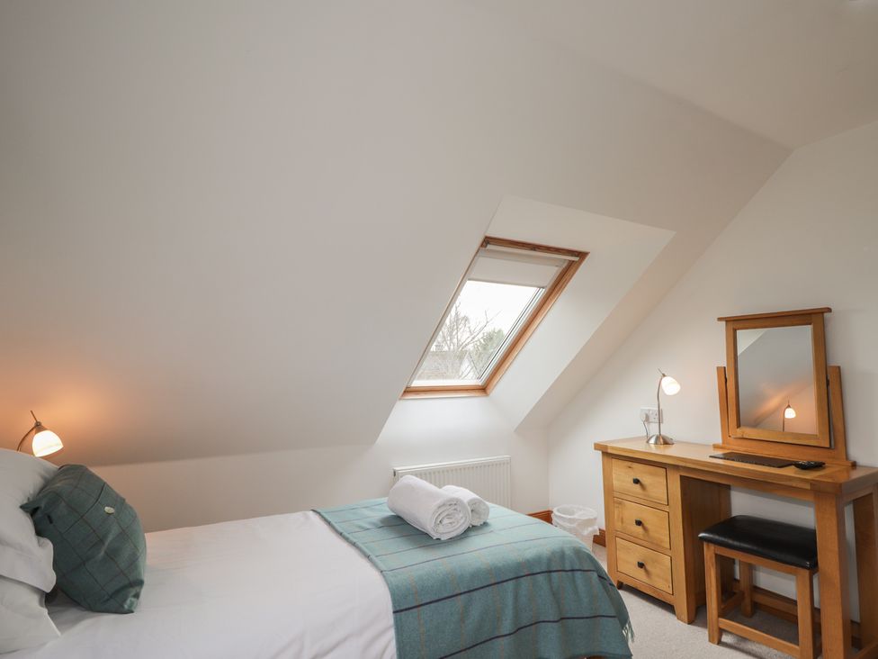 A bedroom with a bed, desk, and window at Little Chestnut in Muir of Ord