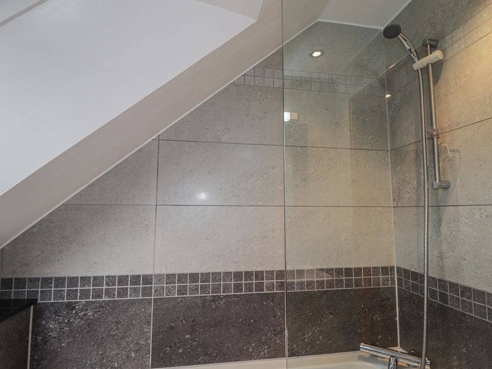 A bathroom with a shower and bathtub at Little Chestnut in Muir of Ord