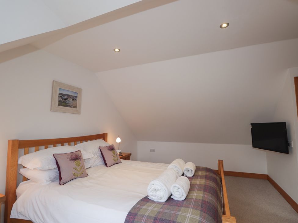 A bedroom with a bed, pillows, and television at Little Chestnut in Muir of Ord