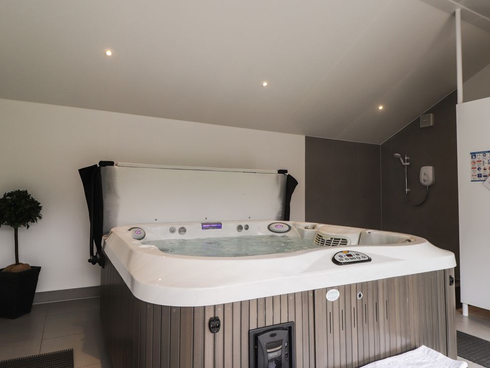 A hot tub with a shower in a bathroom at Little Chestnut in Muir of Ord