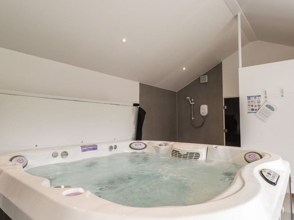 A hot tub with a shower in a bathroom at Little Chestnut in Muir of Ord
