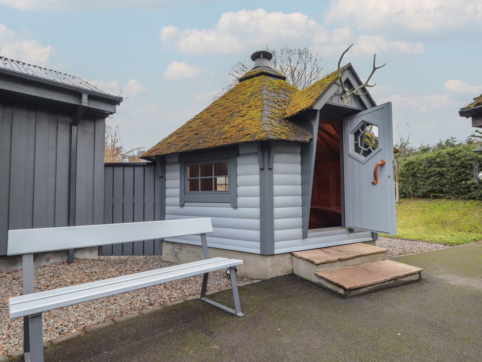 A garden shed with a door open and a bench outside at Little Chestnut in Muir of Ord