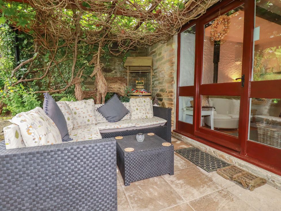 A conservatory with a sofa and coffee table at Wagtail Cottage in East Taphouse