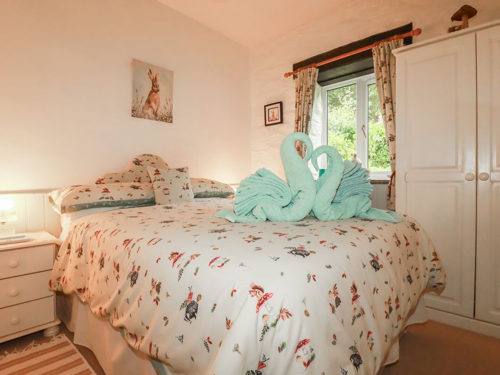 A bedroom with a double bed and decorative towels at Wagtail Cottage East Taphouse