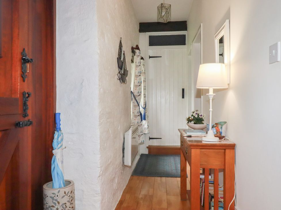 A hallway with wooden door and table at Wagtail Cottage in East Taphouse