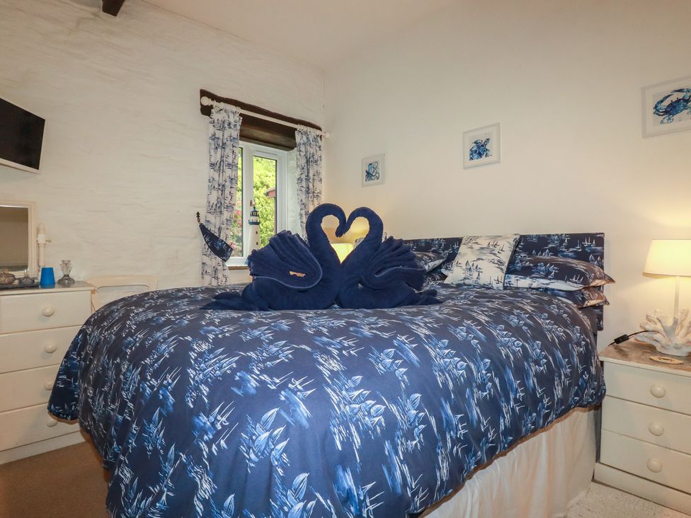 A bedroom with a bed and towel swans at Wagtail Cottage in East Taphouse