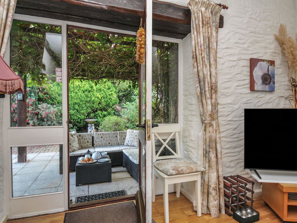 A living room with door and view of garden at Wagtail Cottage in East Taphouse