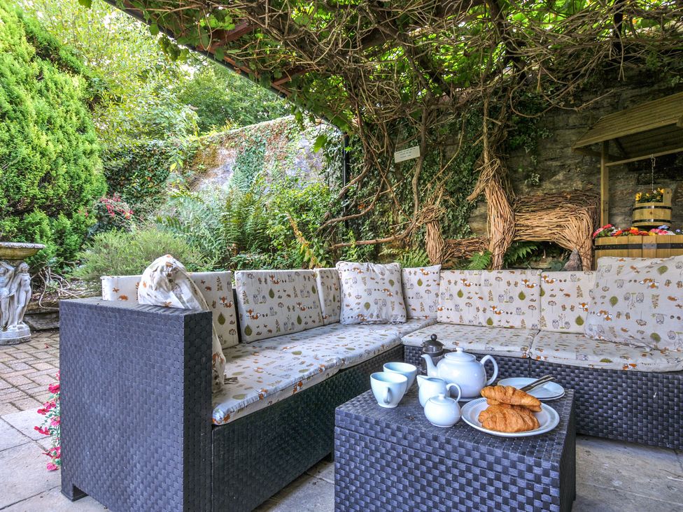 A garden area with a sofa, coffee table, and breakfast items at Wagtail Cottage East Taphouse