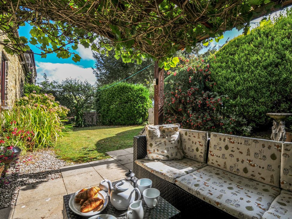 A garden with a sofa and tea set at Wagtail Cottage East Taphouse