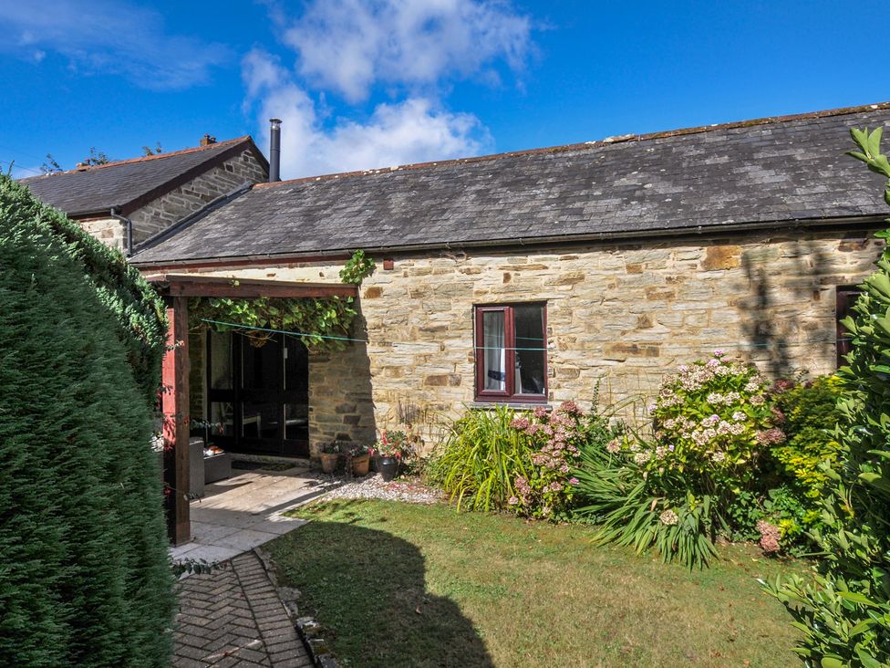 A garden with stone walls and a pathway at Wagtail Cottage in East Taphouse
