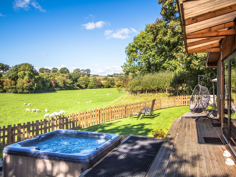 An outdoor space with a hot tub and seating area at Sycamore Lodge Nantmel near Rhayader