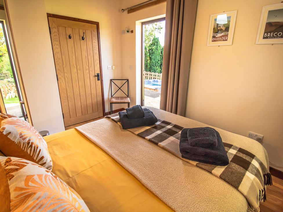 A bedroom with a bed and towels arranged at Sycamore Lodge Nantmel near Rhayader
