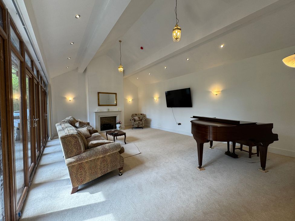 A living room with a piano and a sofa at Plas Glyndwr in Crickhowell