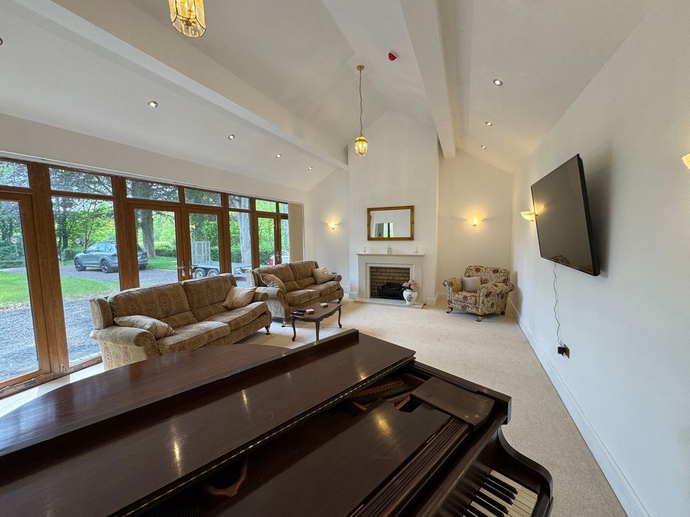 A living room with a piano and seating at Plas Glyndwr in Crickhowell