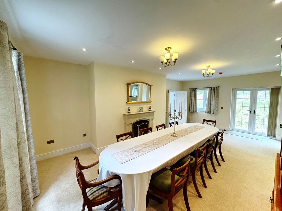 A dining room with a long table and chairs at Plas Glyndwr in Crickhowell