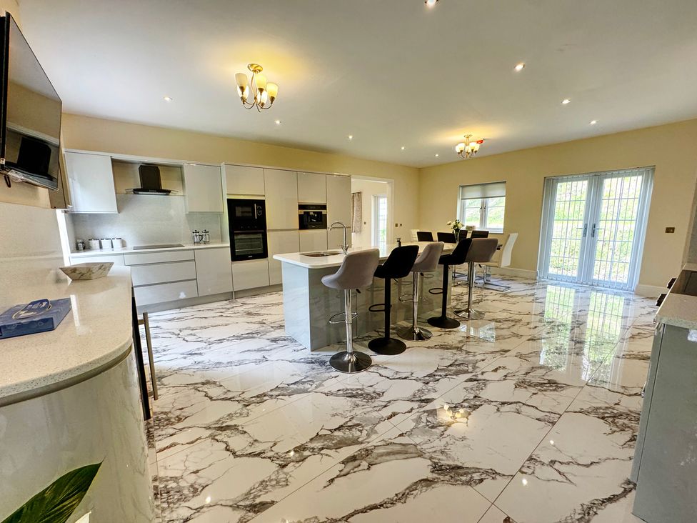 A kitchen with an island and stools at Plas Glyndwr in Crickhowell